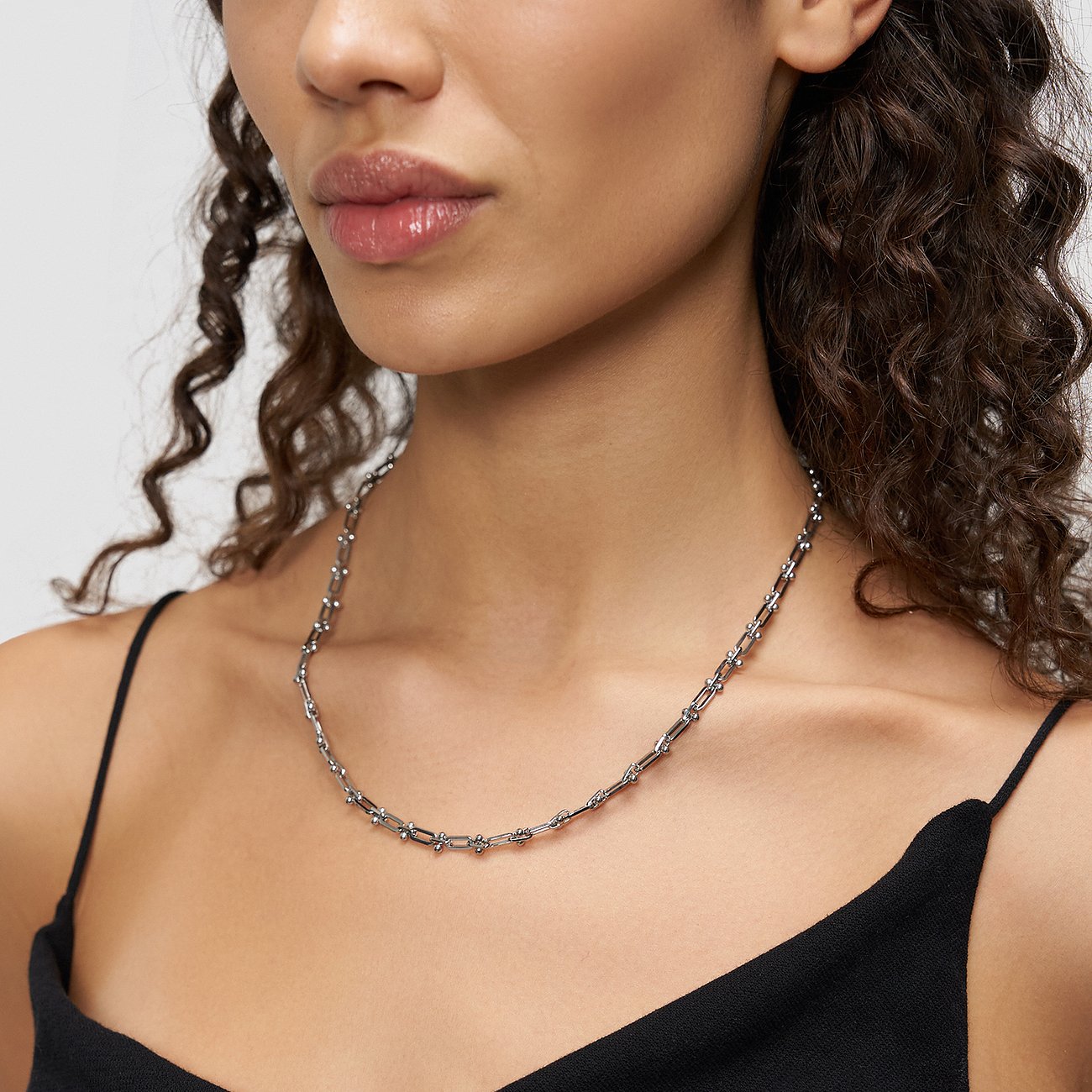 Gros plan d'une femme portant le collier Liebeskind brillant en maillons d'acier inoxydable oblongs et ronds.