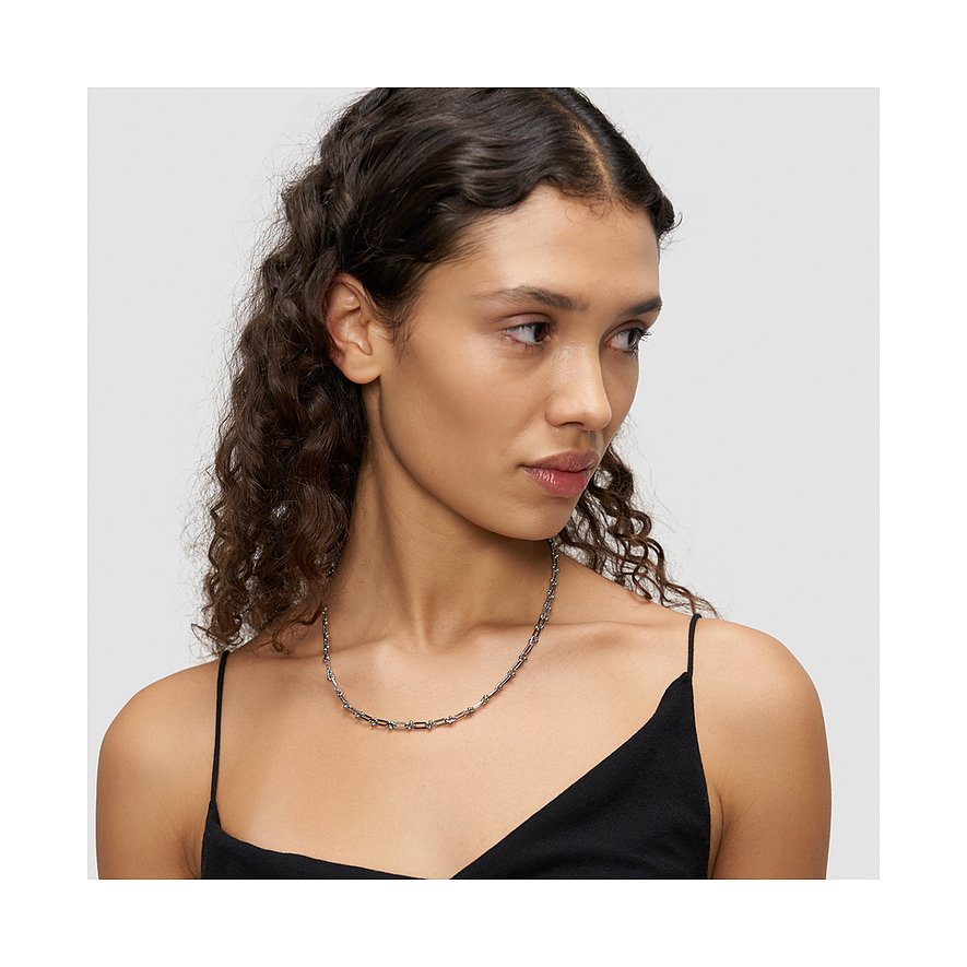 Une femme porte un collier Liebeskind en acier inoxydable, composé de petites billes et de bâtonnets alternés.