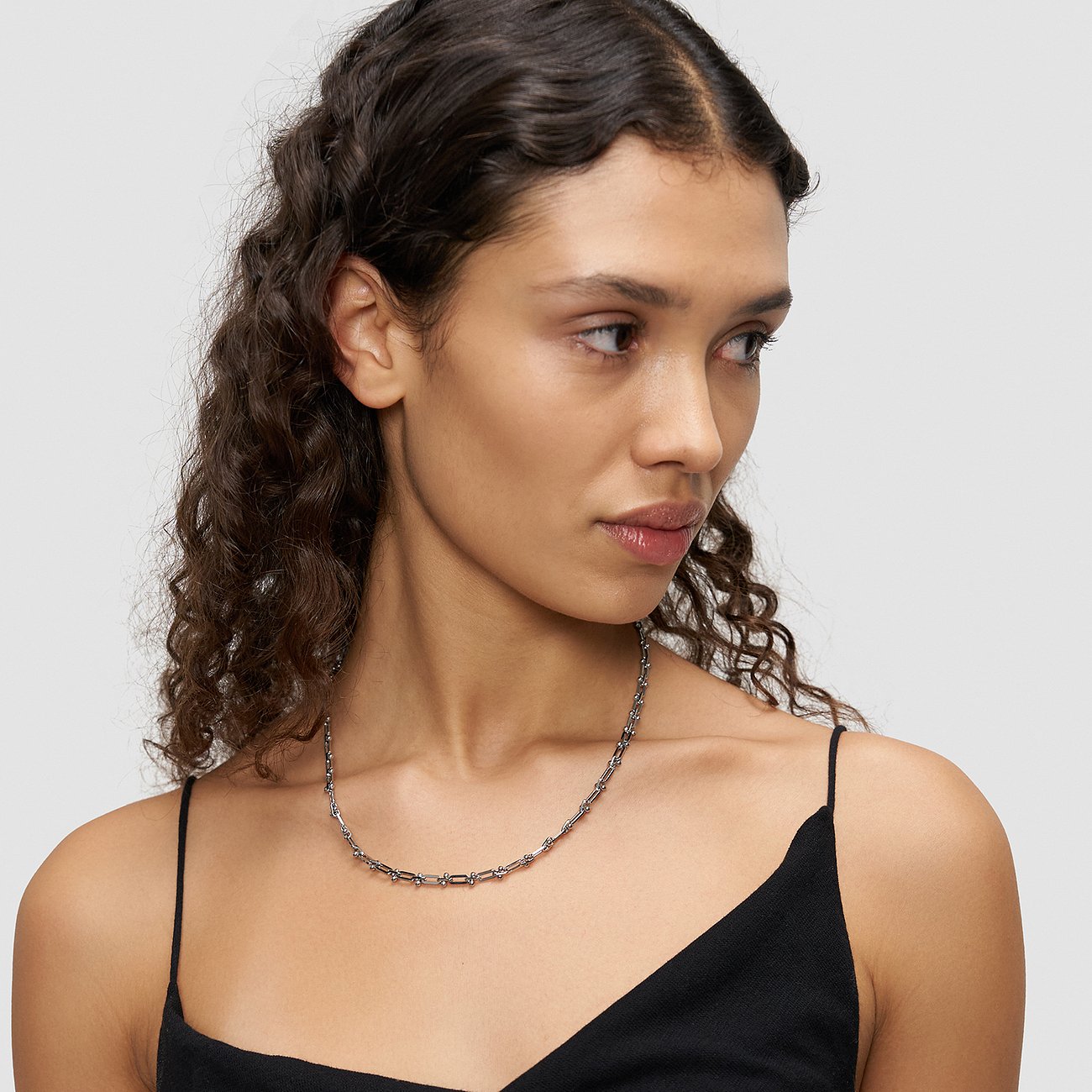 Une femme porte un collier Liebeskind en acier inoxydable, composé de petites billes et de bâtonnets alternés.