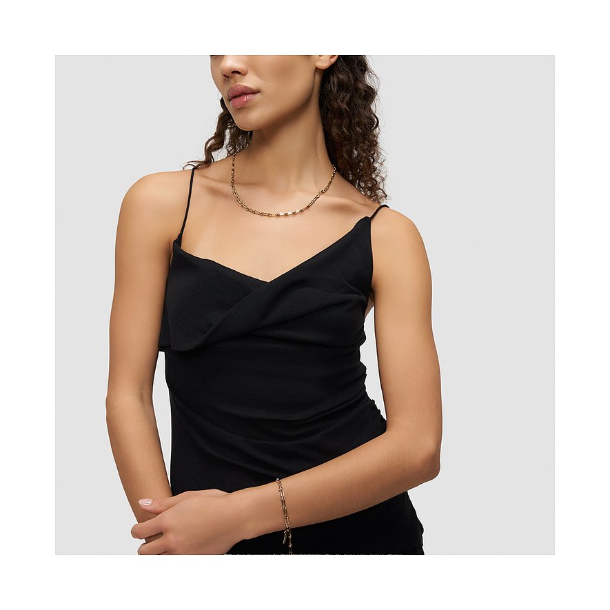 Modellen bär ett Liebeskind halsband och matchande armband i guldfärgat rostfritt stål med en svart topp.