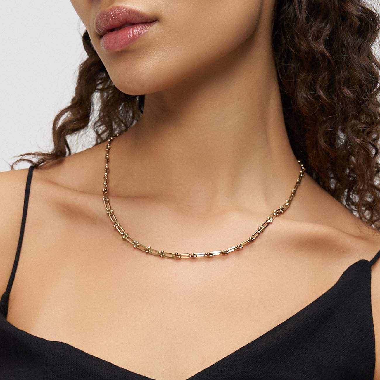 Liebeskind guld, rostfritt stålhalsband buret av kvinna, med små och avlånga länkar.
