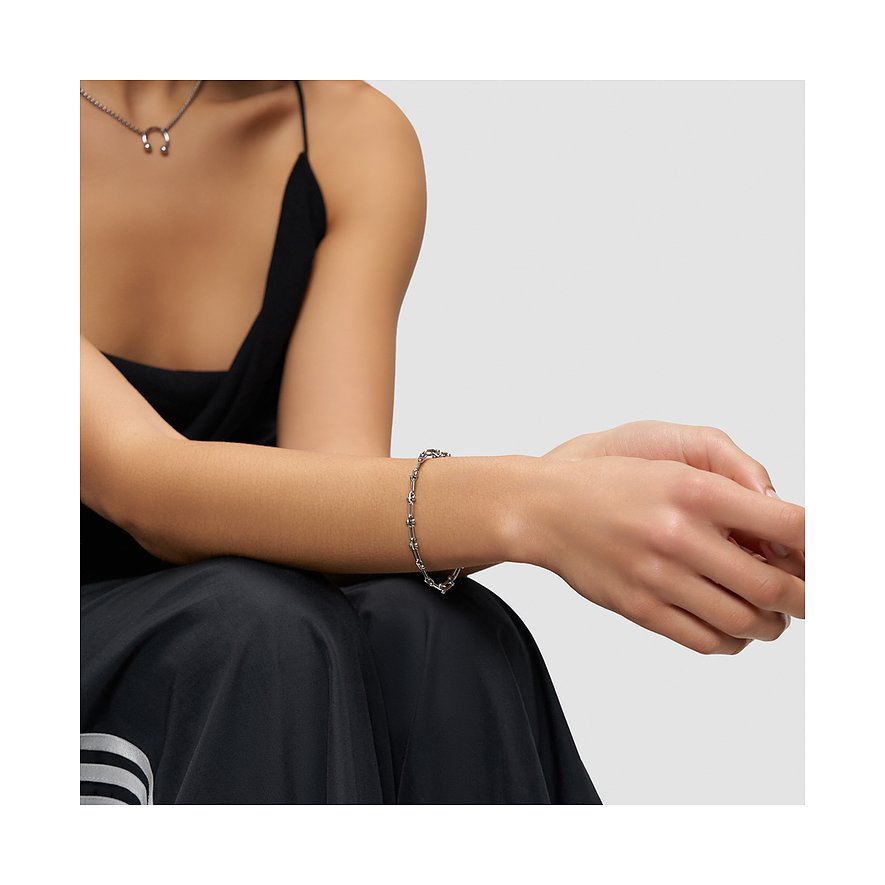 Am Handgelenk einer Person getragenes Liebeskind Armband aus Edelstahl mit Kettengliedern und Knoten.