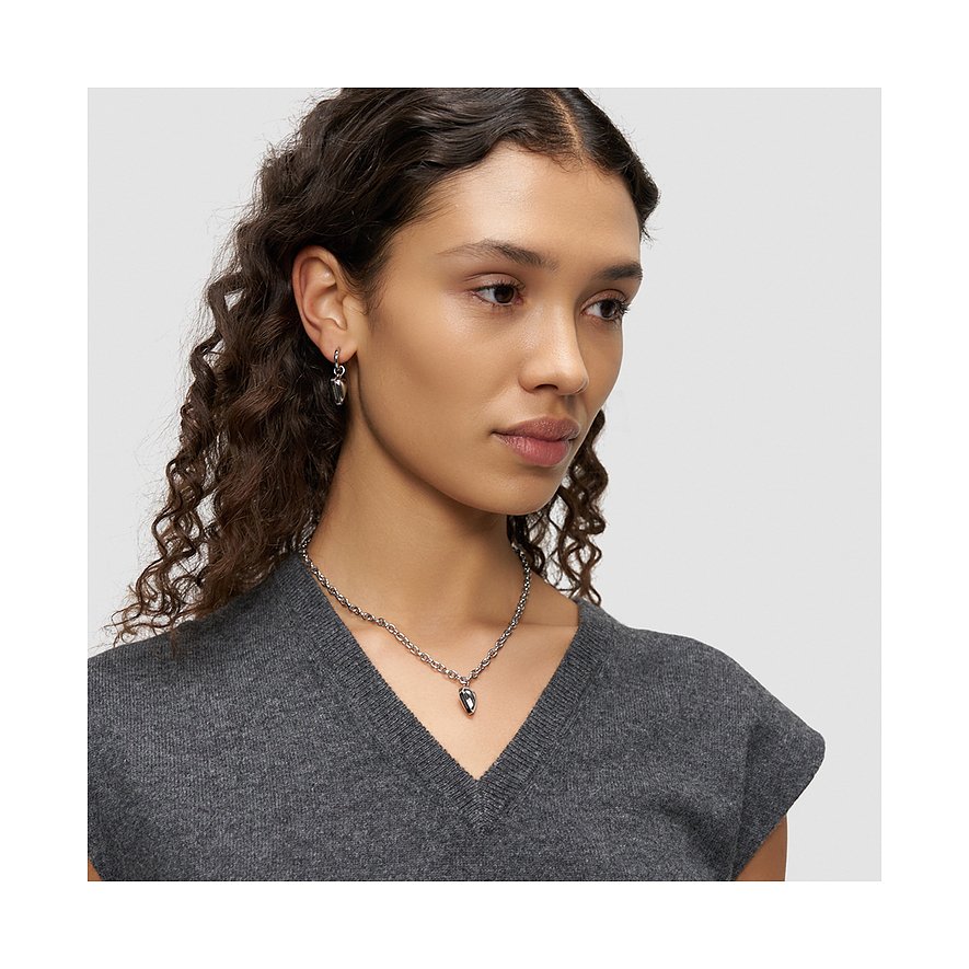 Model draagt een Liebeskind roestvrijstalen ketting en oorbellen. De ketting heeft een hanger.