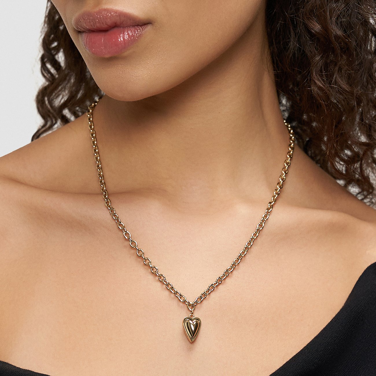 Close-up van een vrouw met een Liebeskind goudkleurige roestvrijstalen ketting met hartjeshanger.