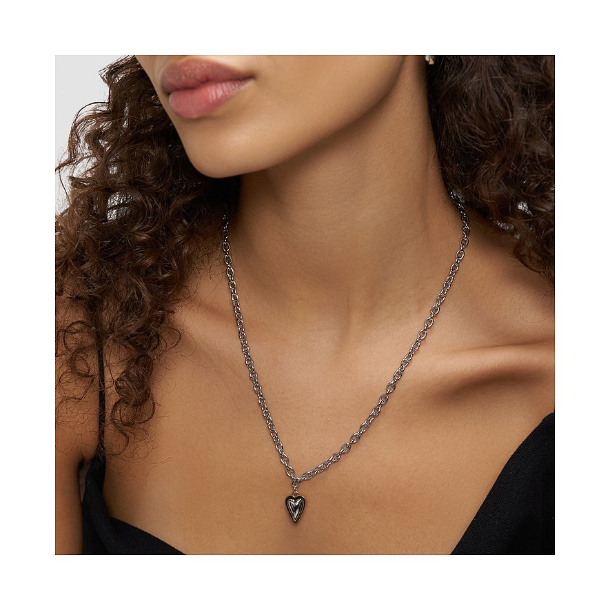 Een vrouw draagt een lange Liebeskind roestvrijstalen ketting met een glanzende hartvormige hanger.
