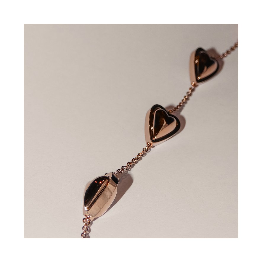 Close-up van een roségouden Liebeskind roestvrijstalen ketting met drie hartvormige hangers op witte achtergrond.