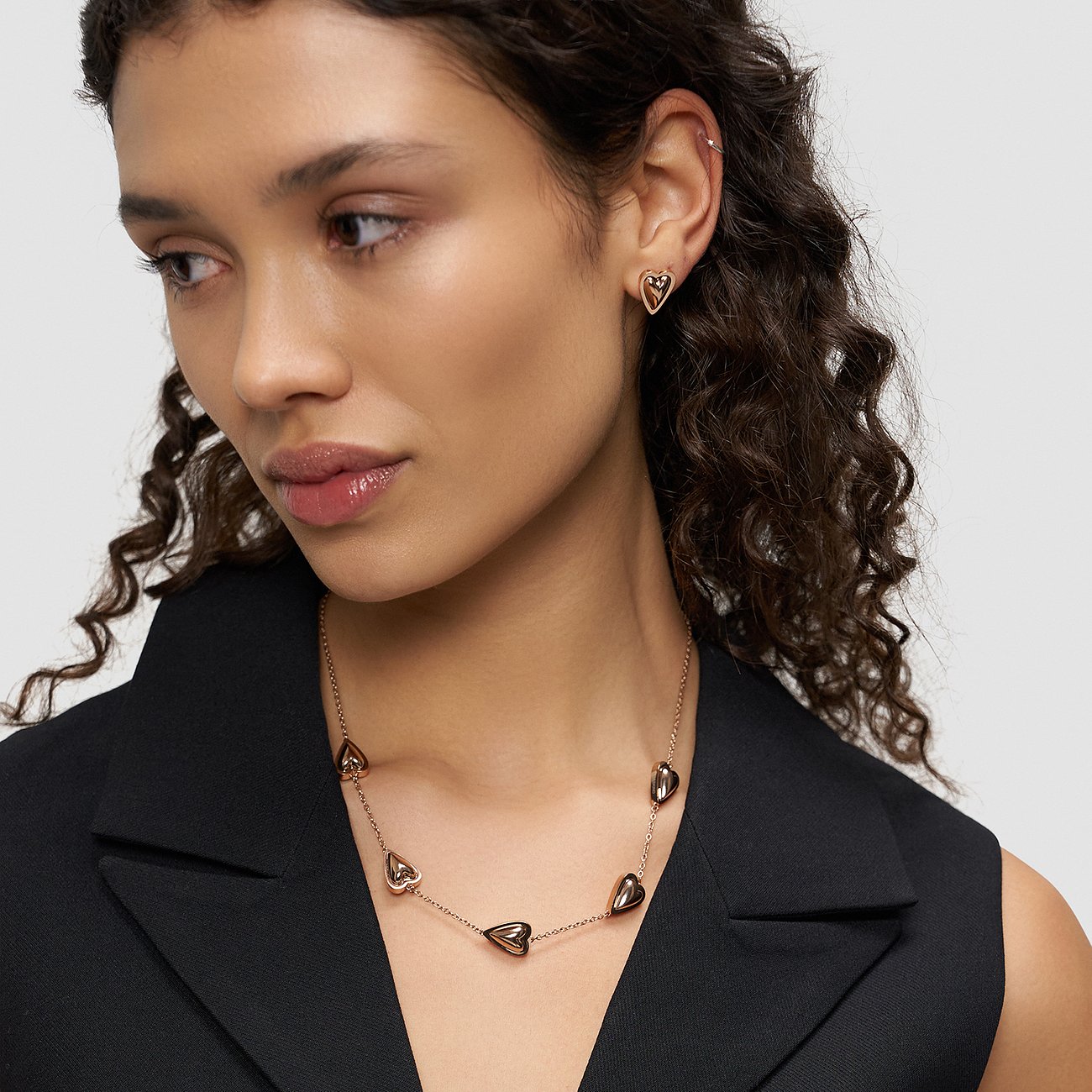 Een model draagt een Liebeskind ketting van roségoudkleurig roestvrij staal met hartvormige hangers.