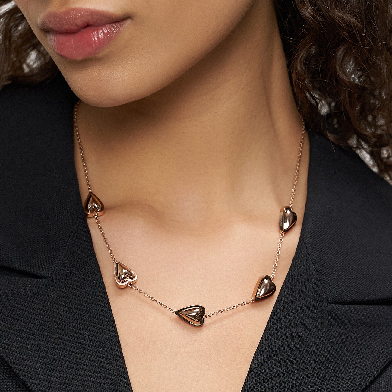 Close-up van een vrouw met een roségoudkleurige Liebeskind RVS ketting, bezet met zes harten.