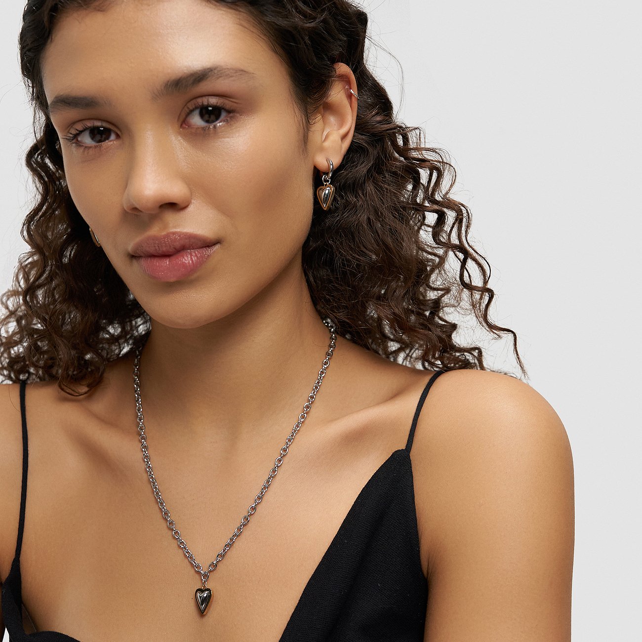 Eine Frau trägt Liebeskind Ohrringe aus Edelstahl, die als Ohrschmuck dienen und mit einem Herzanhänger versehen sind.