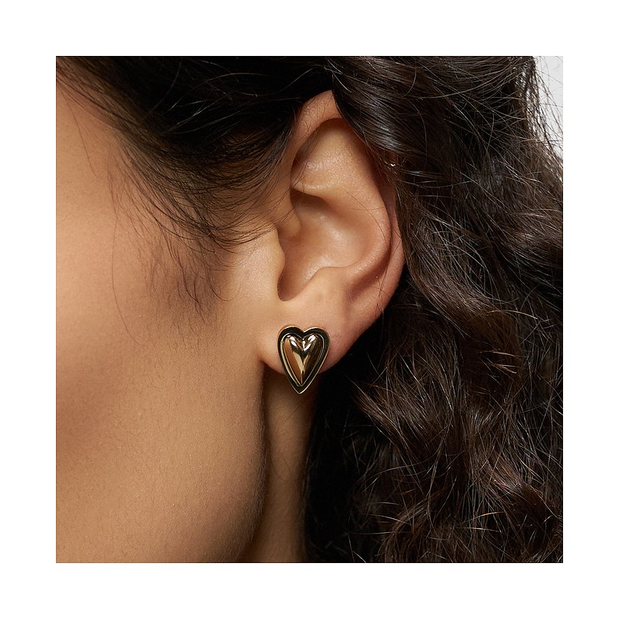 Ein golden schimmernder Herz-Ohrstecker aus Liebeskind Edelstahl am Ohr getragen, sichtbar durch dunkles Haar.