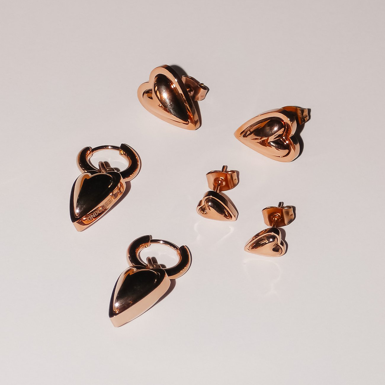 Liebeskind Ohrschmuck aus roségoldfarbenem Edelstahl. Set mit zwei Ohrhängern und vier Herz-Ohrsteckern.