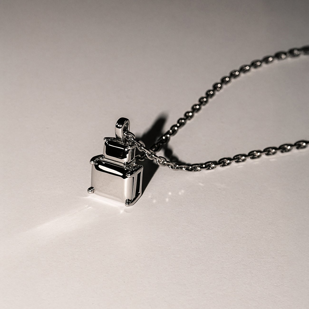 Gros plan d'un collier Liebeskind en acier inoxydable avec un pendentif de deux blocs rectangulaires brillants empilés.