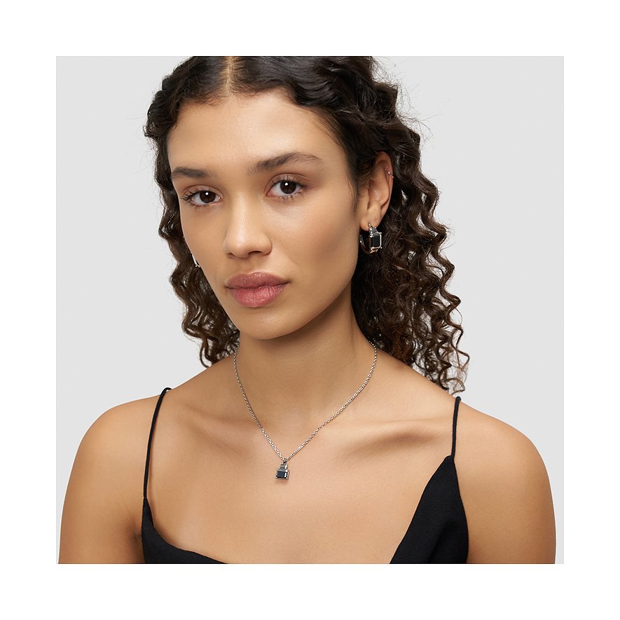 Une femme porte un collier Liebeskind en acier inoxydable avec un pendentif carré foncé.