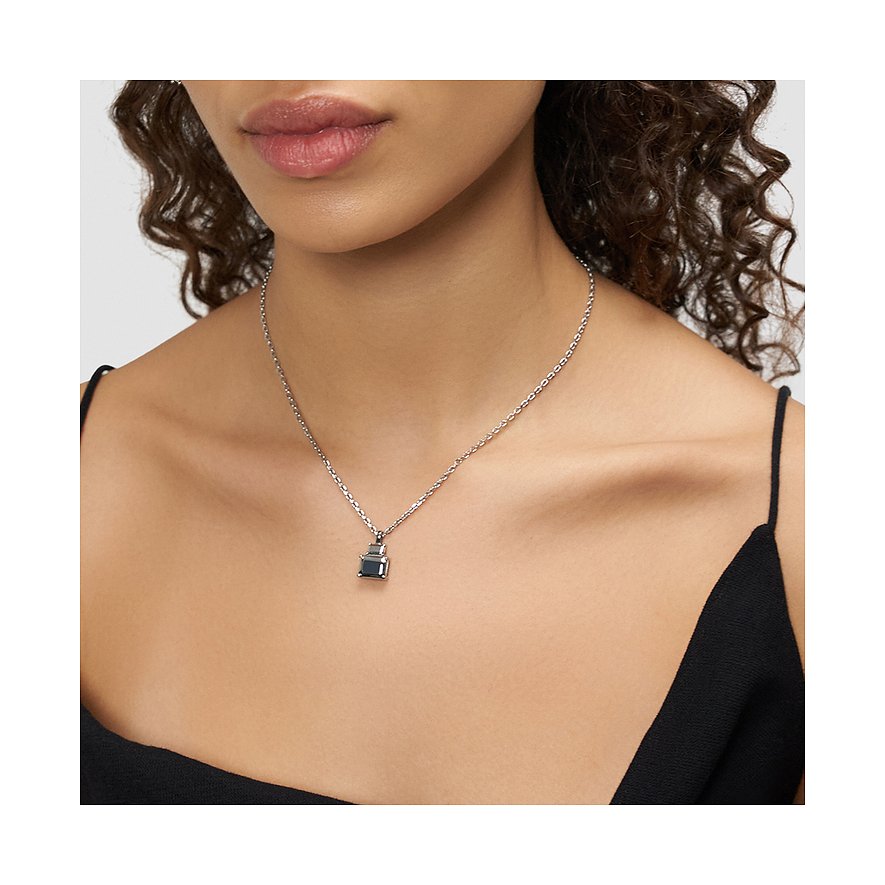 Une femme porte un collier Liebeskind en acier inoxydable avec un petit pendentif gris foncé.