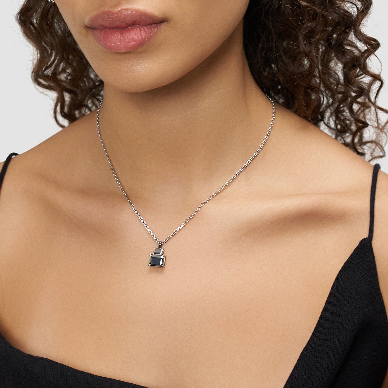 Une femme porte un collier Liebeskind en acier inoxydable avec un petit pendentif gris foncé.
