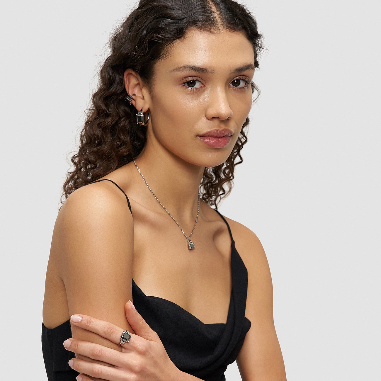 Model trägt Liebeskind Ohrschmuck aus Edelstahl, der stilvolle Creolen und einen Stern-Ohrstecker kombiniert.