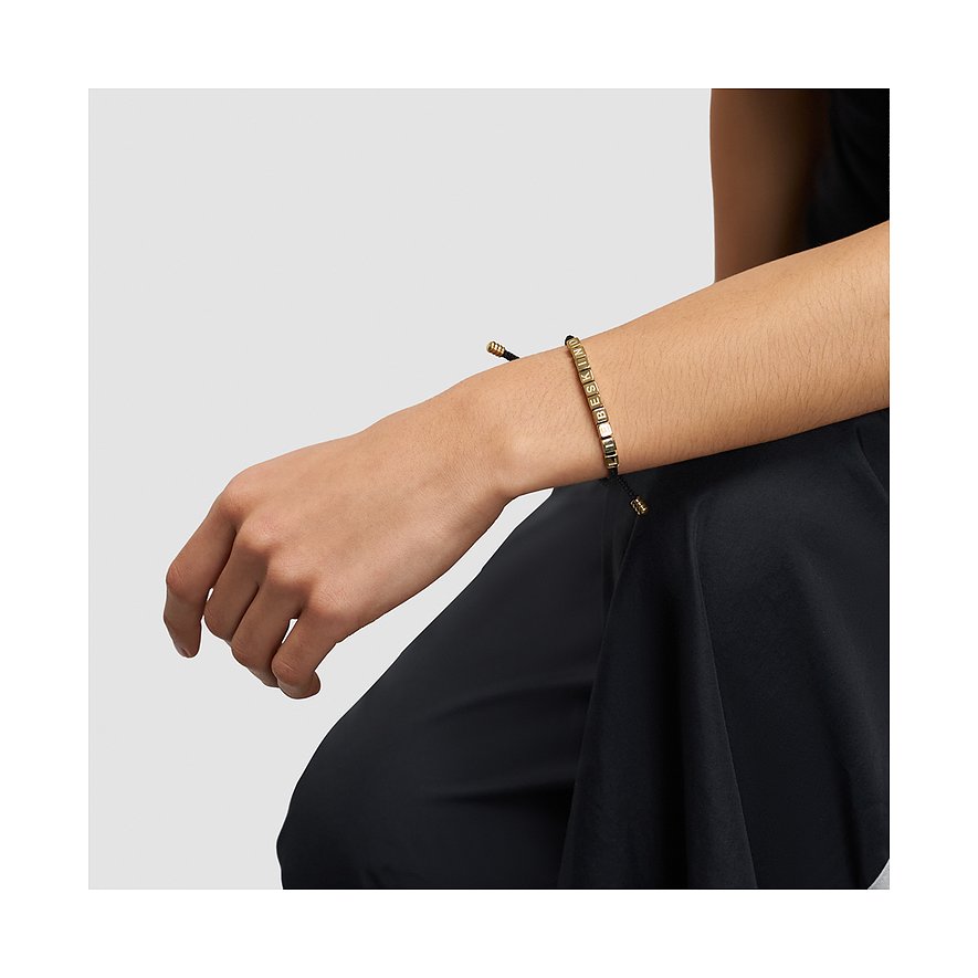 Am Handgelenk getragenes Liebeskind Armband aus Edelstahl mit goldenen Beads, die das Wort ‘LIEBESKIND’ bilden.