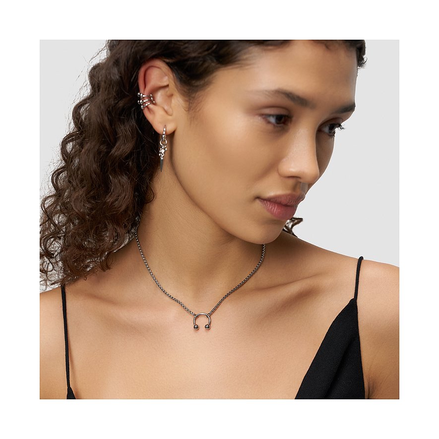 Model wears a Liebeskind necklace with a horseshoe pendant, matching earrings, and ear cuffs, all in shiny stainless steel.