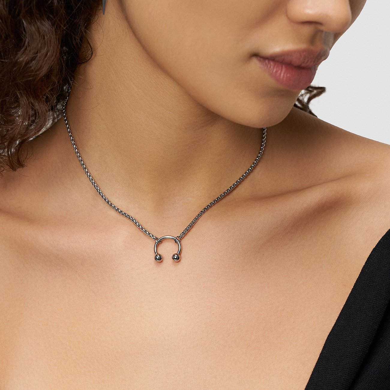 Eng anliegende Liebeskind Halsschmuck-Kette aus Edelstahl mit schlichtem Hufeisen-Anhänger am Hals einer Person.