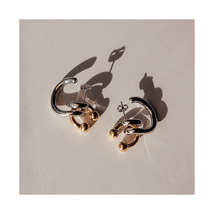 Ein Paar Ohrschmuck von Liebeskind aus Edelstahl, mit silber- und goldfarbenen C-förmigen Elementen und kleinen Kugeln.