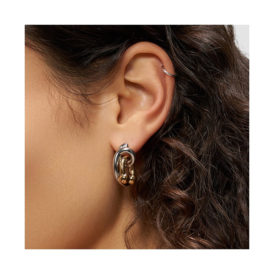 Am Ohr einer Person ist ein Liebeskind Ohrschmuck aus Edelstahl zu sehen, der silberne und goldfarbene Elemente kombiniert.