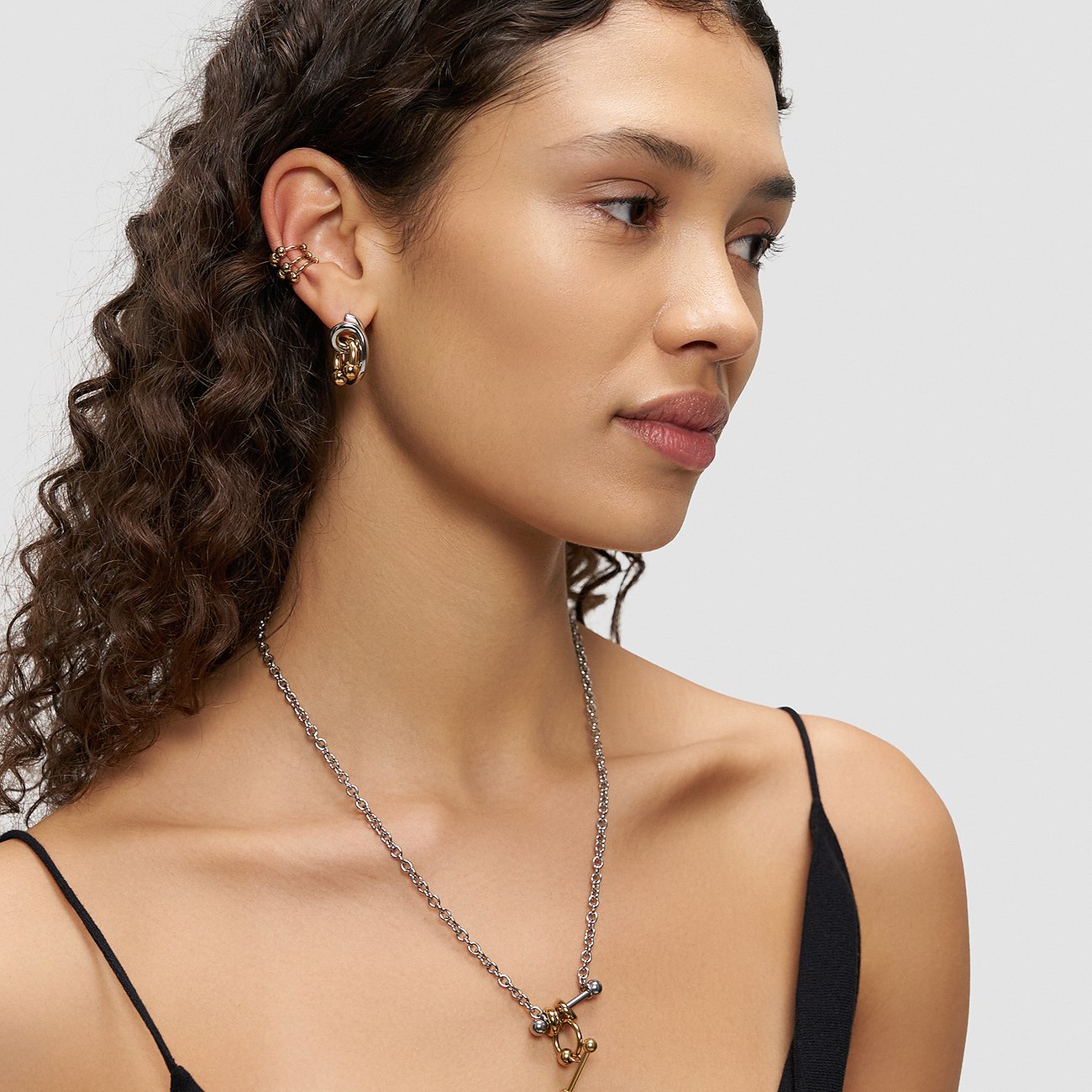 Eine Frau trägt Liebeskind Ohrschmuck aus Edelstahl, bestehend aus goldenen und silberfarbenen Ohrringen und einem Ear Cuff.