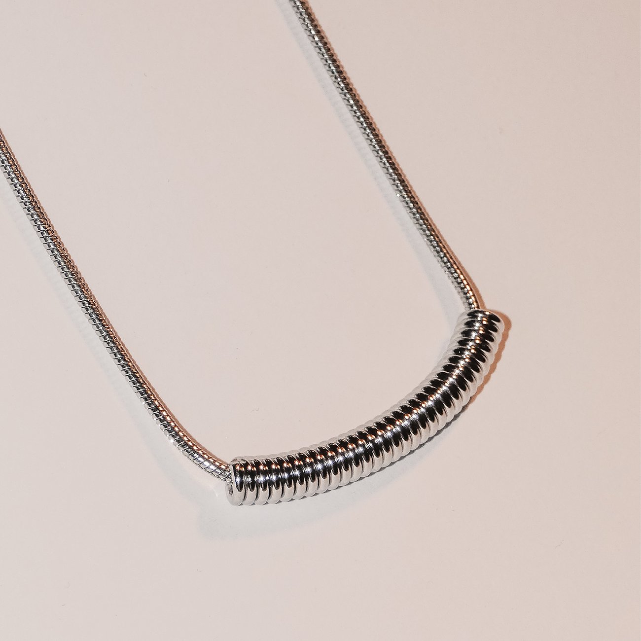 Liebeskind roestvrijstalen halsketting met een gebogen, geribbeld hangertje aan een slangenketting.