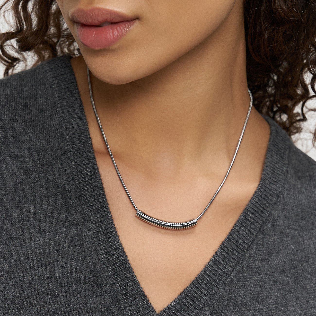 Close-up van een vrouw met een Liebeskind roestvrijstalen ketting met een horizontale buis.