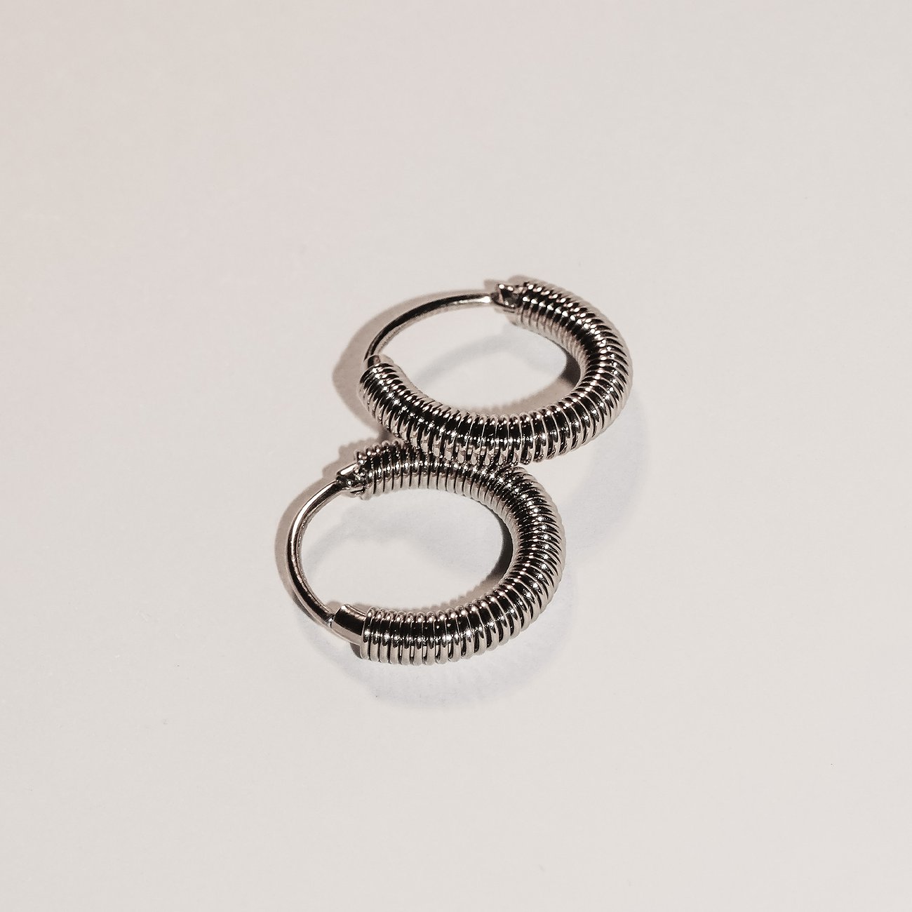 Zwei Liebeskind Creolen aus Edelstahl in Silber. Die Ohrringe haben eine spiralförmige Rillenstruktur.