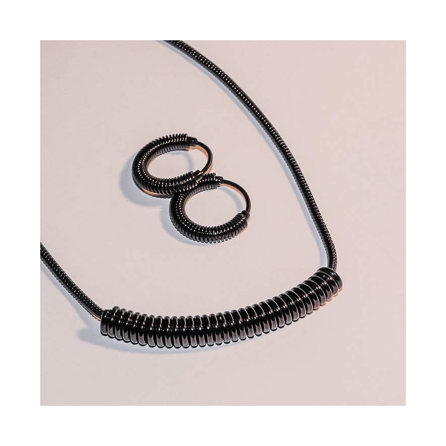 Deux créoles Liebeskind en acier inoxydable noir et nervuré sont posées à côté d'un collier Liebeskind assorti.