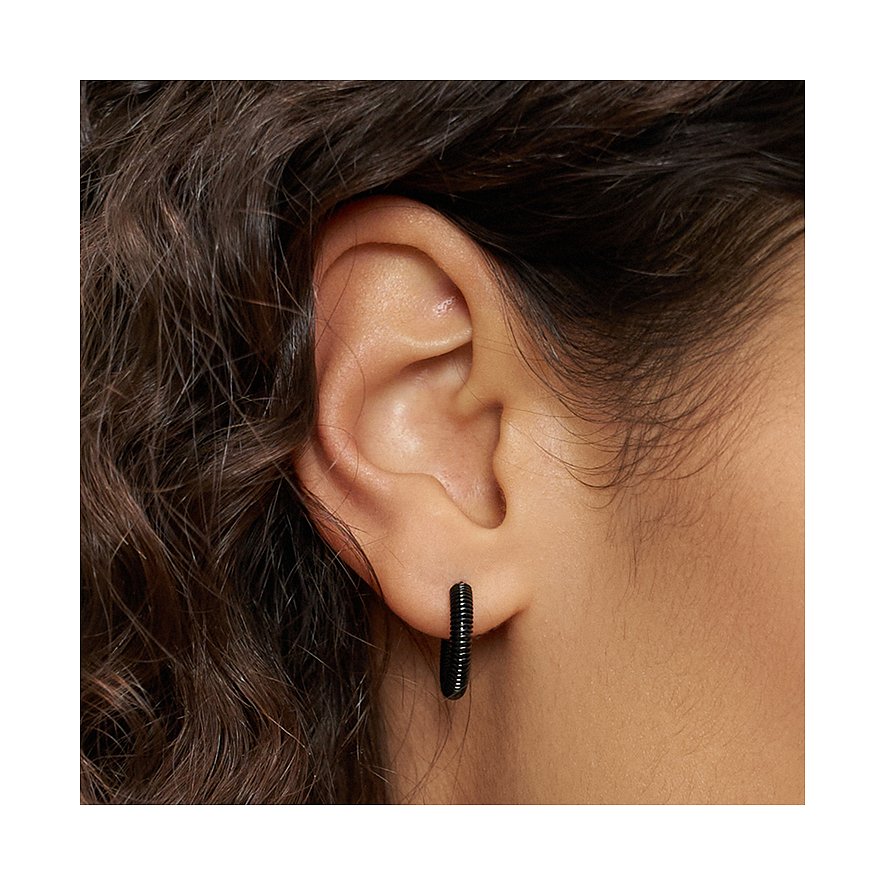 Gros plan d'une personne portant un bijou d'oreille Liebeskind noir en acier inoxydable, présentant une texture rainurée.