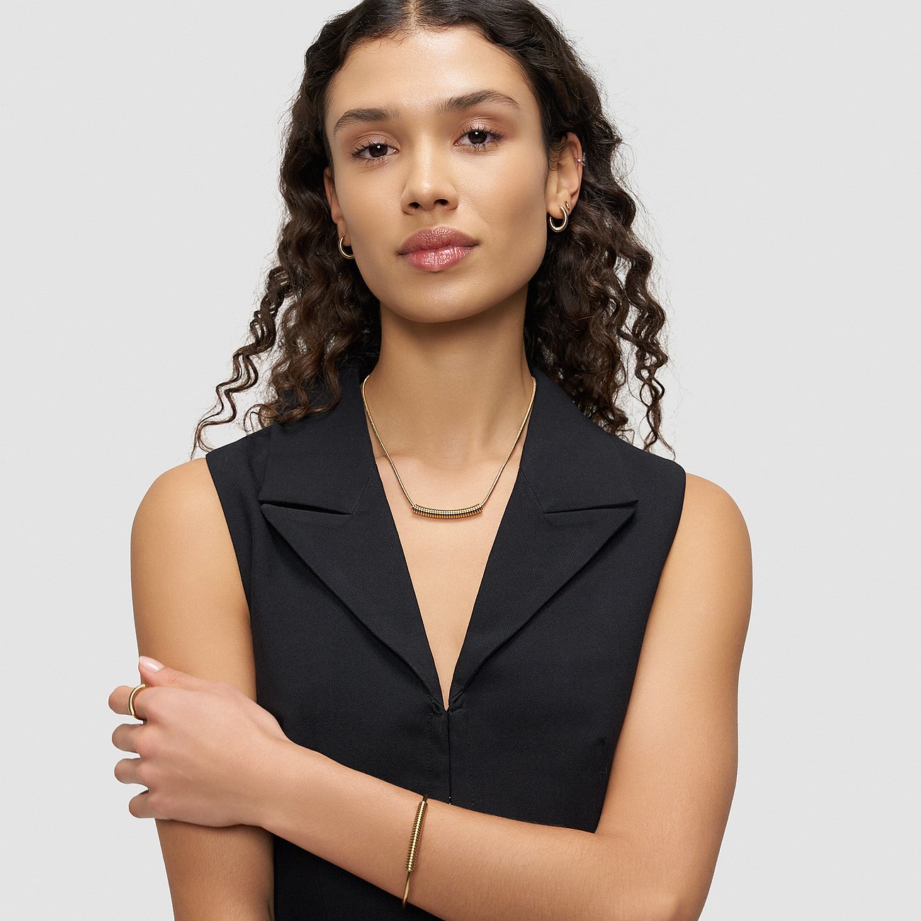 Een vrouw draagt een gouden Liebeskind roestvrijstalen armband met een eenvoudig, langwerpig ontwerp.