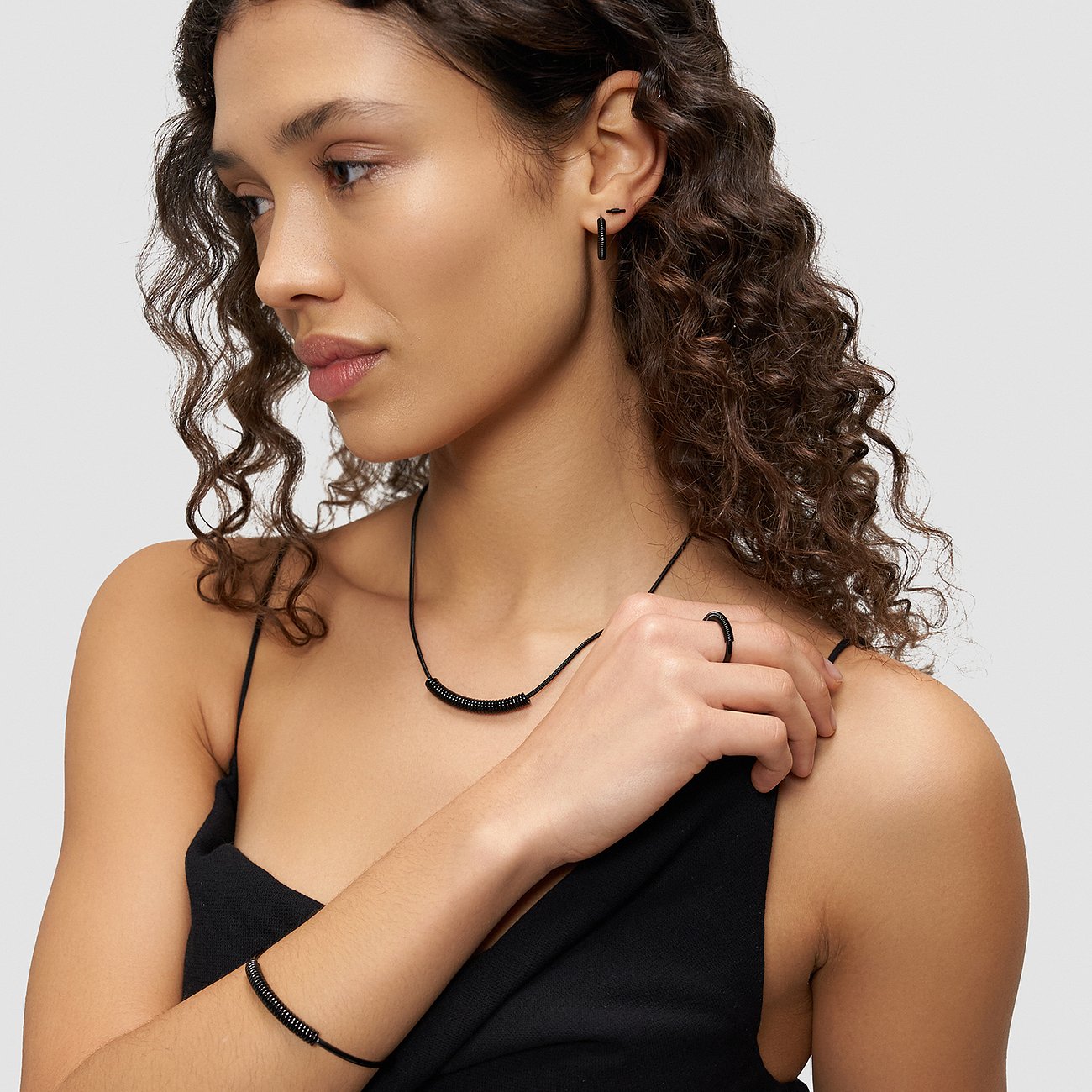 Eine Frau trägt ein passendes Set aus schwarzen Liebeskind Edelstahl-Armschmuck und Ohrringen.
