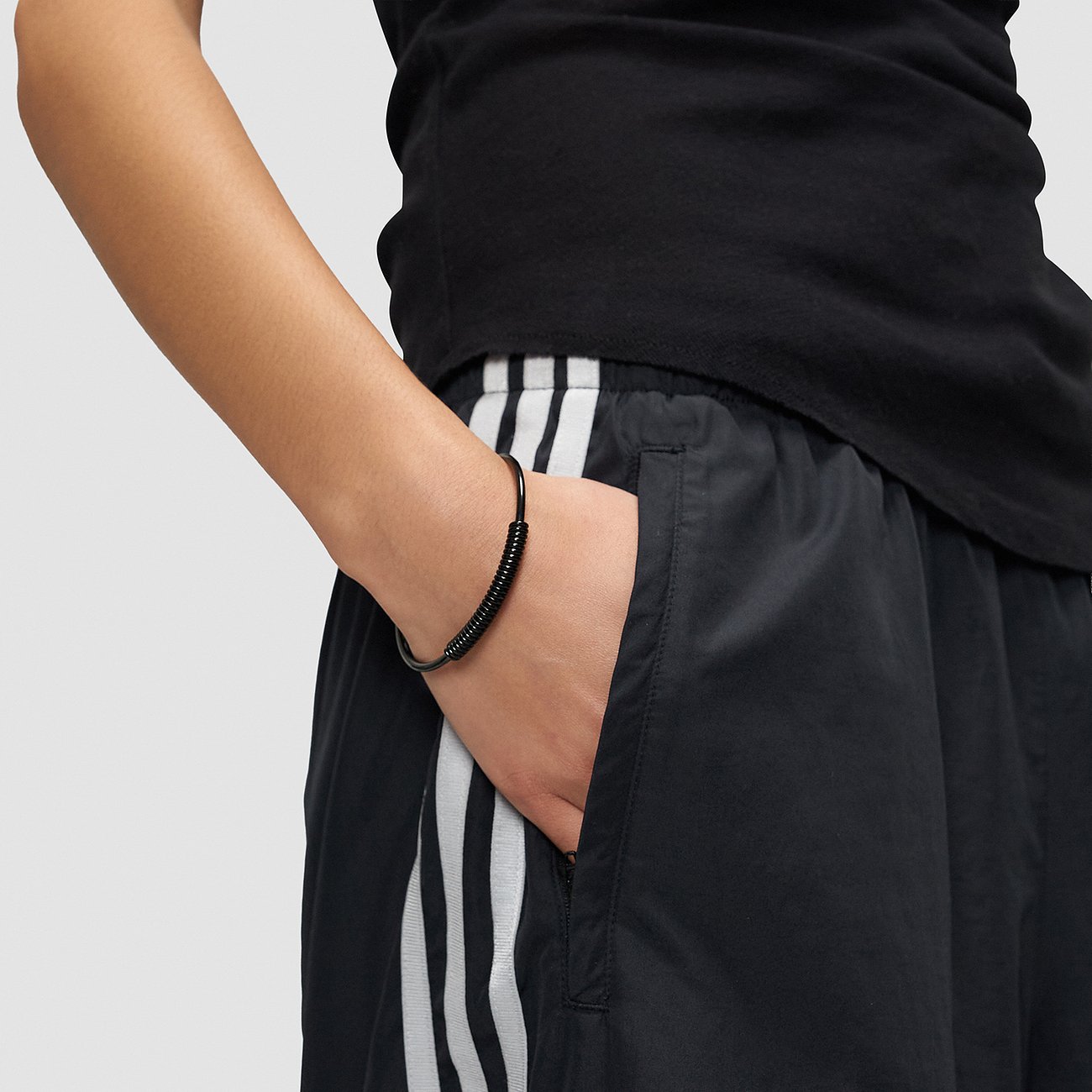 Am Handgelenk einer Person ist ein schwarzes Liebeskind Armschmuck aus Edelstahl zu sehen.