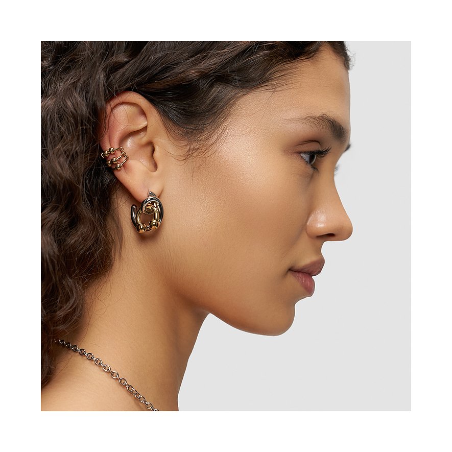 Model bærer Liebeskind smykkesæt i rustfrit stål, bestående af guld- og sorte øreringe og ear cuffs.