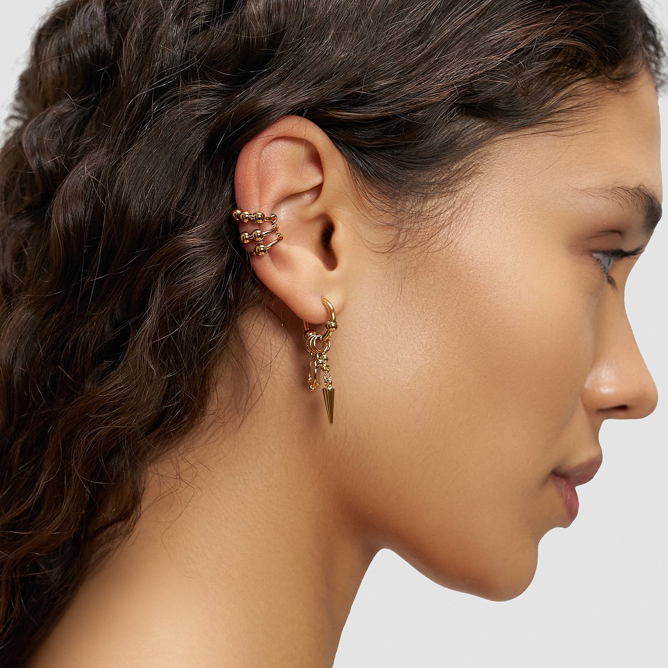 Liebeskind-øreringe i guldfarvet stål. Ear cuff med kugler, kreol med spids vedhæng.