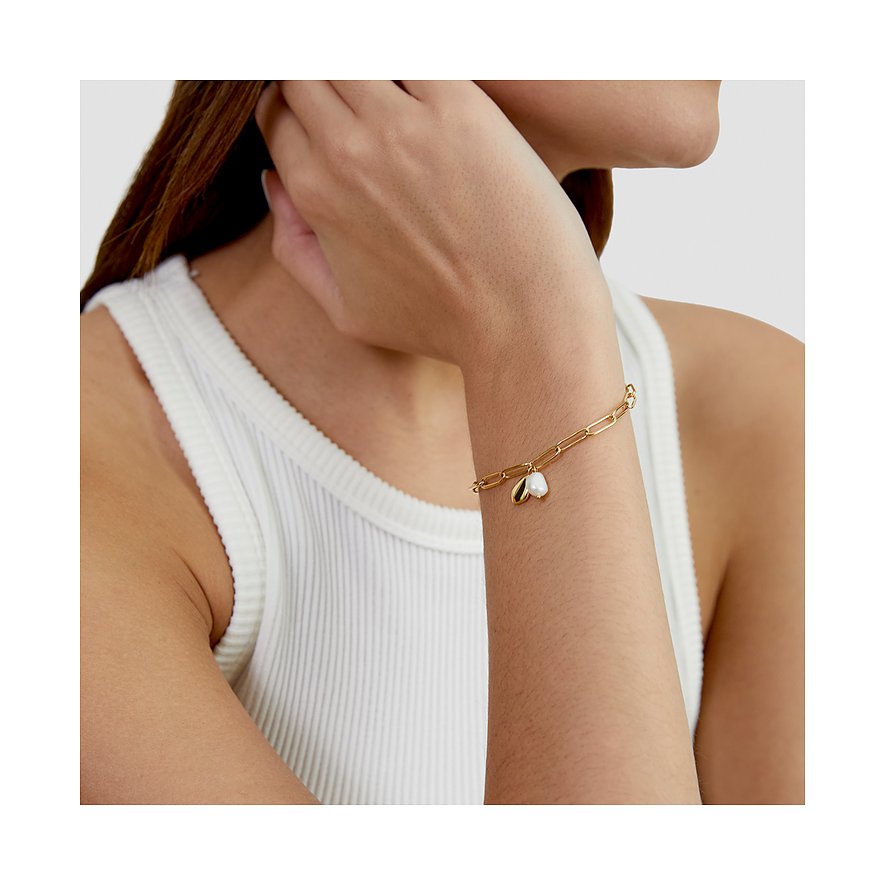 s.Oliver Armschmuck aus gelb-goldenem Edelstahl an einem Frauenarm, mit weißem herzförmigem Motiv.