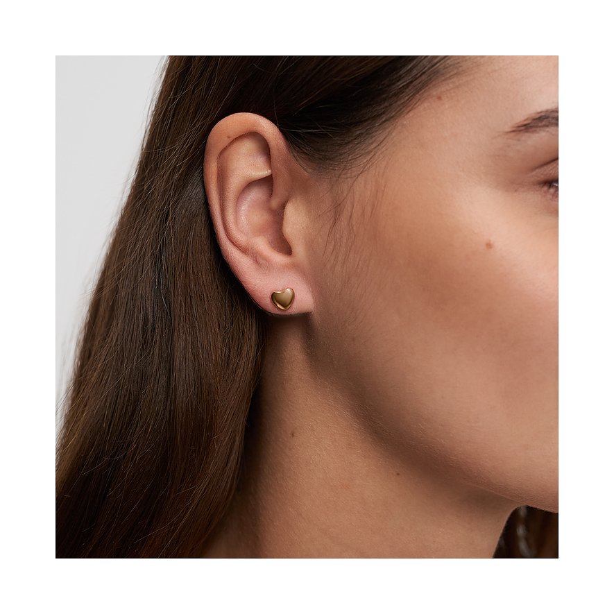 Gros plan d'une boucle d'oreille s.Oliver en forme de cœur en acier inoxydable doré, portée par un mannequin.