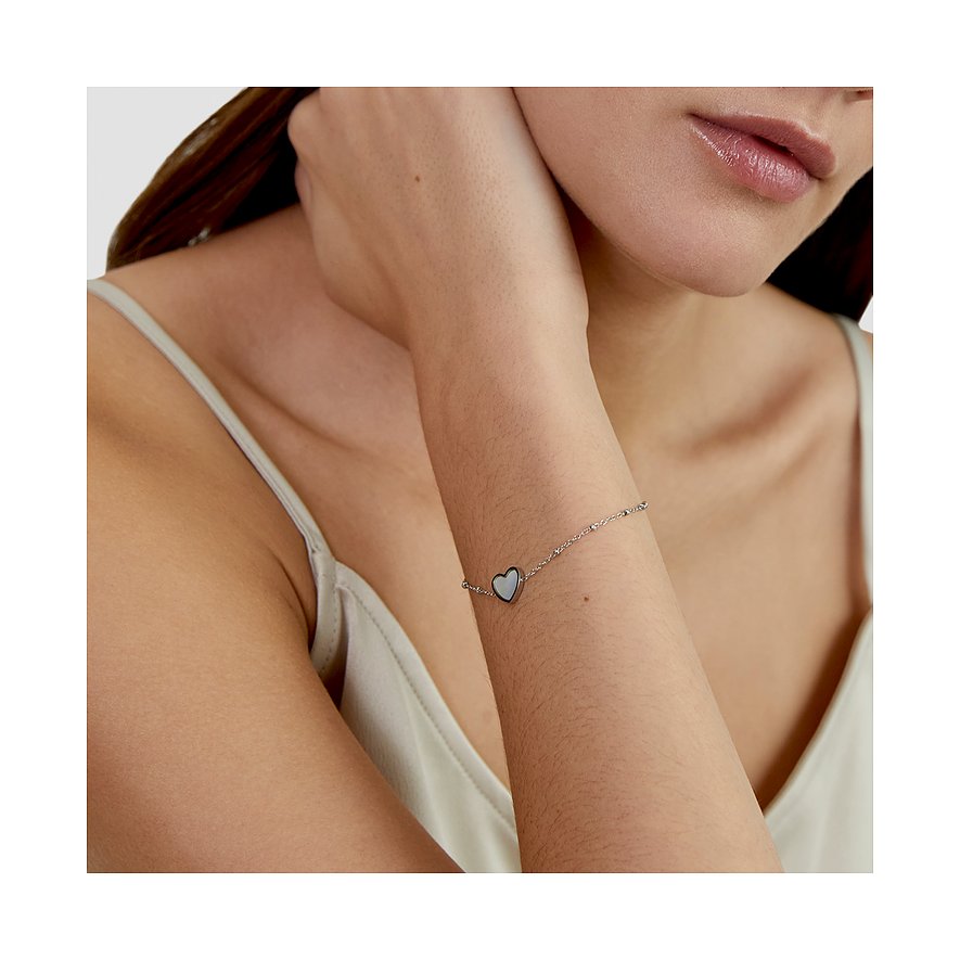 Am Arm einer Frau ist das s.Oliver Edelstahl-Armband mit einem Herz-Anhänger aus perlmuttfarbenem Stein zu sehen.