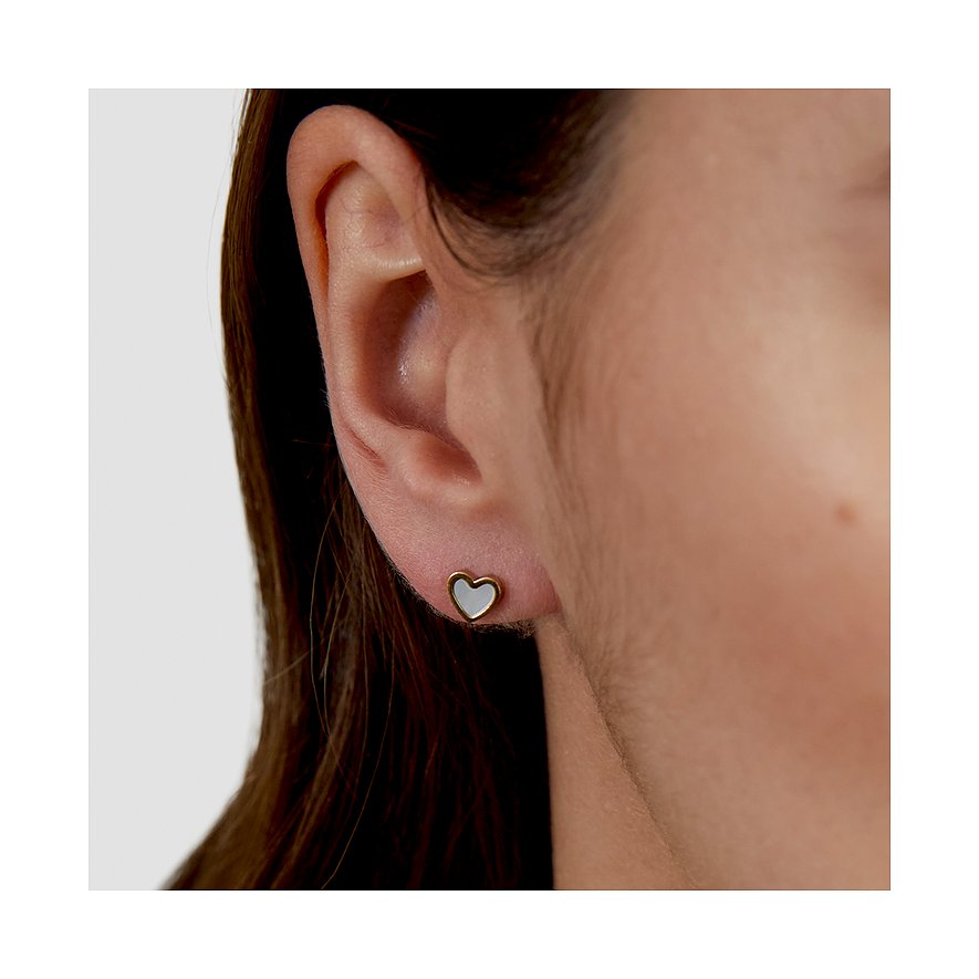 Gros plan : oreille droite avec petite boucle d'oreille cœur s.Oliver dorée en acier inoxydable. Centre du cœur blanc, nacré.