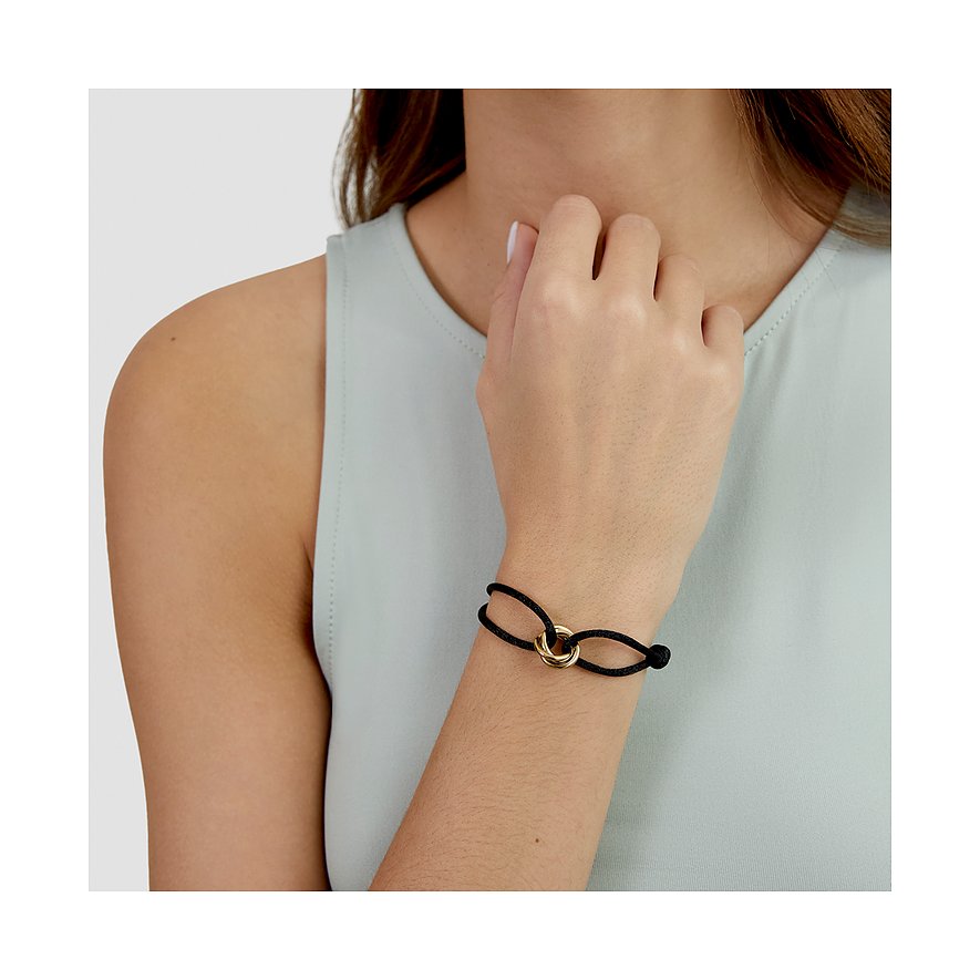 Frau trägt s.Oliver Armband aus schwarzem Textil mit goldfarbenem Edelstahl-Ring am linken Handgelenk.