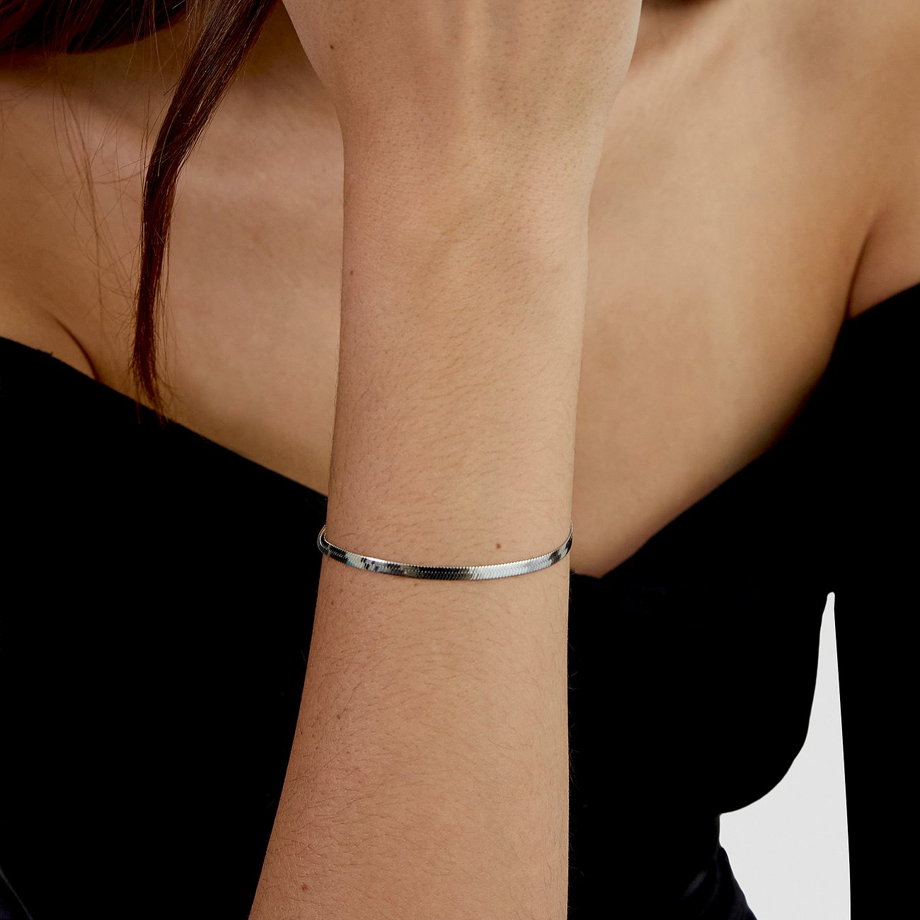 s.Oliver Armband aus glänzendem Edelstahl, in Form einer flachen Schlangenkette, am Handgelenk getragen.