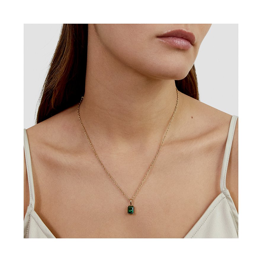 Ein s.Oliver Halsband aus goldfarbenem Edelstahl mit einem rechteckigen Zirkonia in Smaragdgrün, getragen von einem Model.