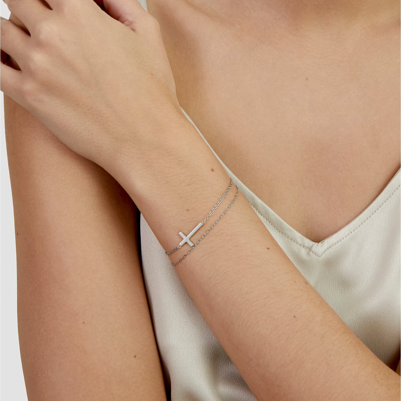 Am Handgelenk einer Frau getragenes s.Oliver Armband aus Edelstahl mit einem schlichten, seitlich platzierten Kreuz.