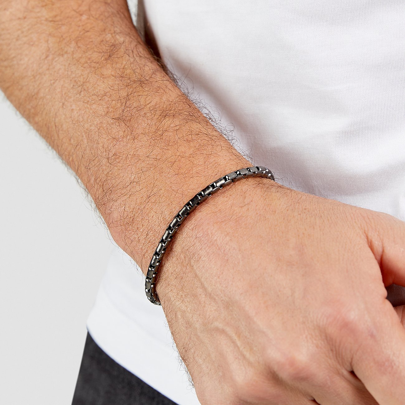 s.Oliver herrarmband i mörkt rostfritt stål, buret på en handled. Kulkedjan har en slät yta.