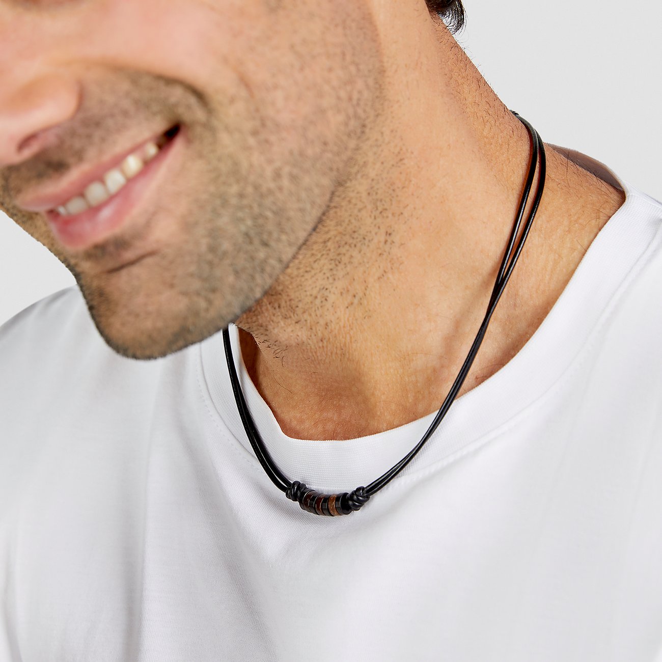 En leende man bär ett s.Oliver halsband i svart läder med ringar i rostfritt stål.
