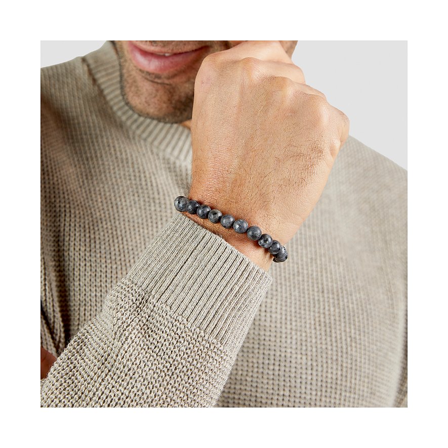 Al polso di un uomo con un maglione beige, si vede un bracciale s.Oliver con pietre scure.