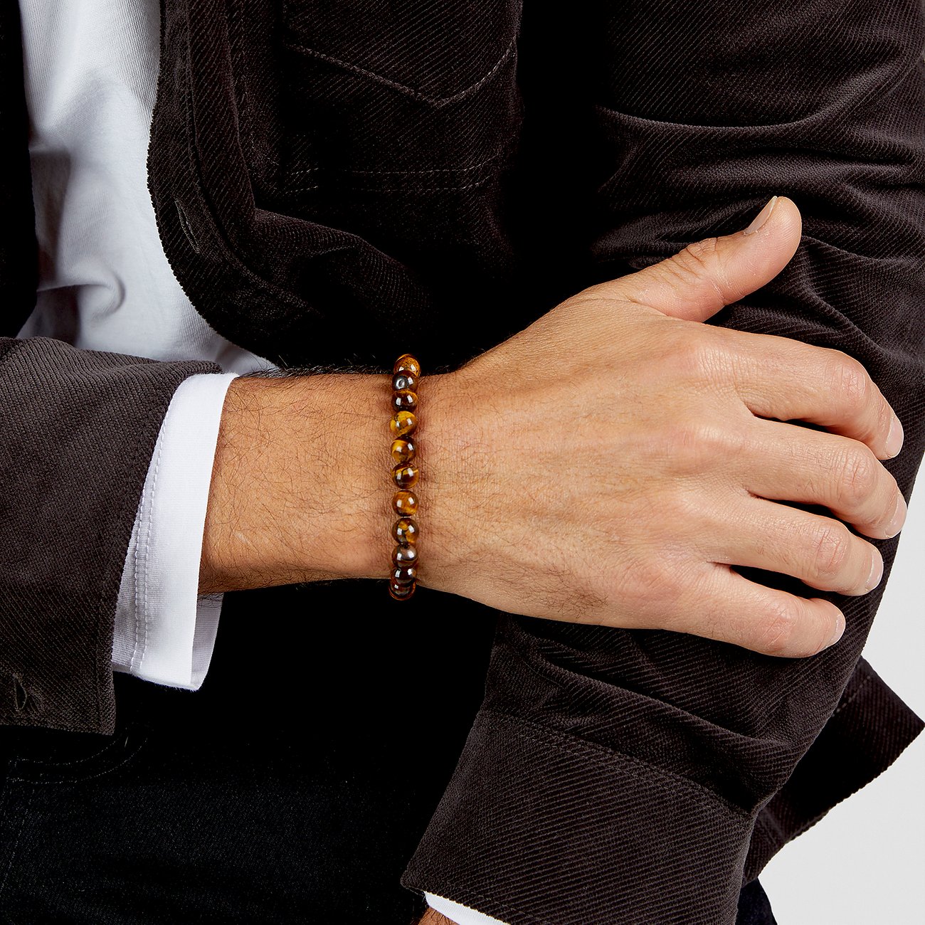 Bracciale uomo s.Oliver in pietre occhio di tigre marroni, indossato su un braccio con giacca scura e camicia bianca.