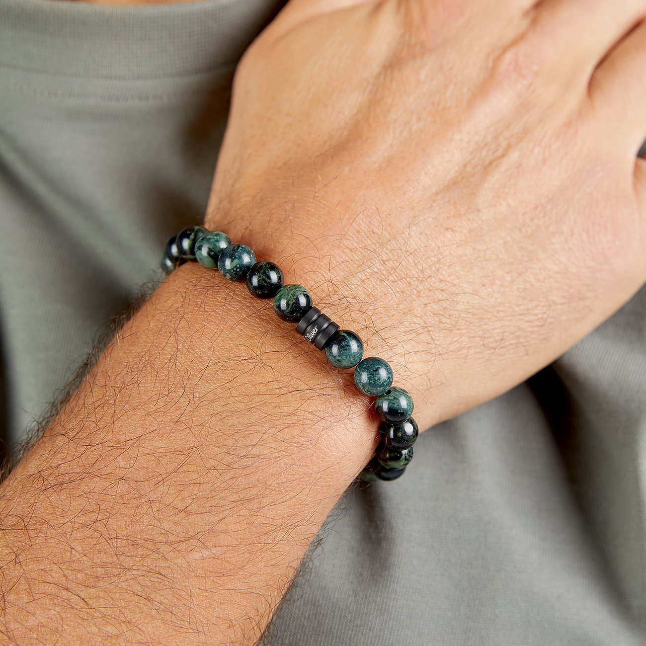 s.Oliver Armschmuck aus dunklen, gemaserten Perlen, akzentuiert durch schwarze Scheiben mit Markenlogo.