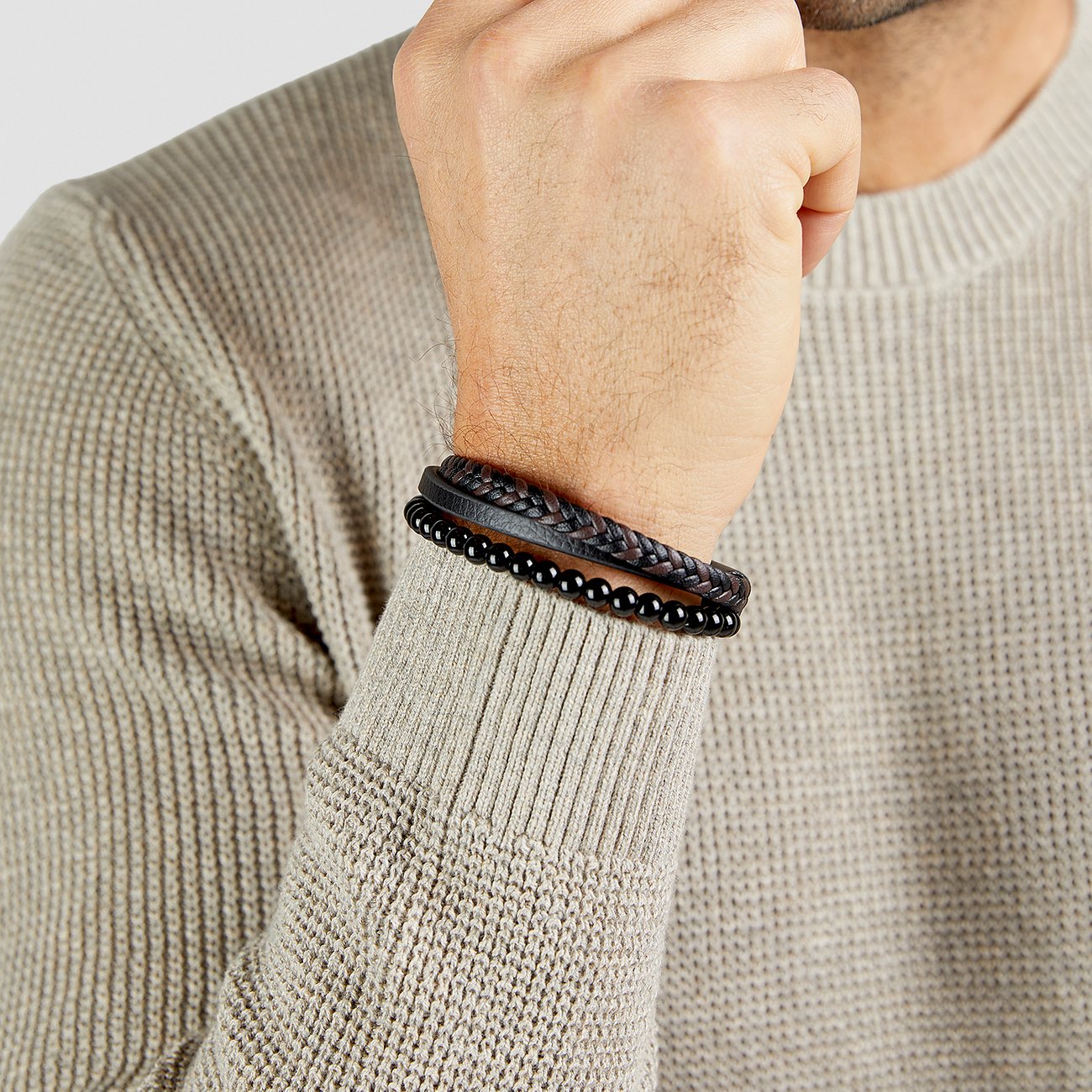 Au poignet d'un homme, un bracelet s.Oliver en cuir tressé et perles d'onyx noir brillant.